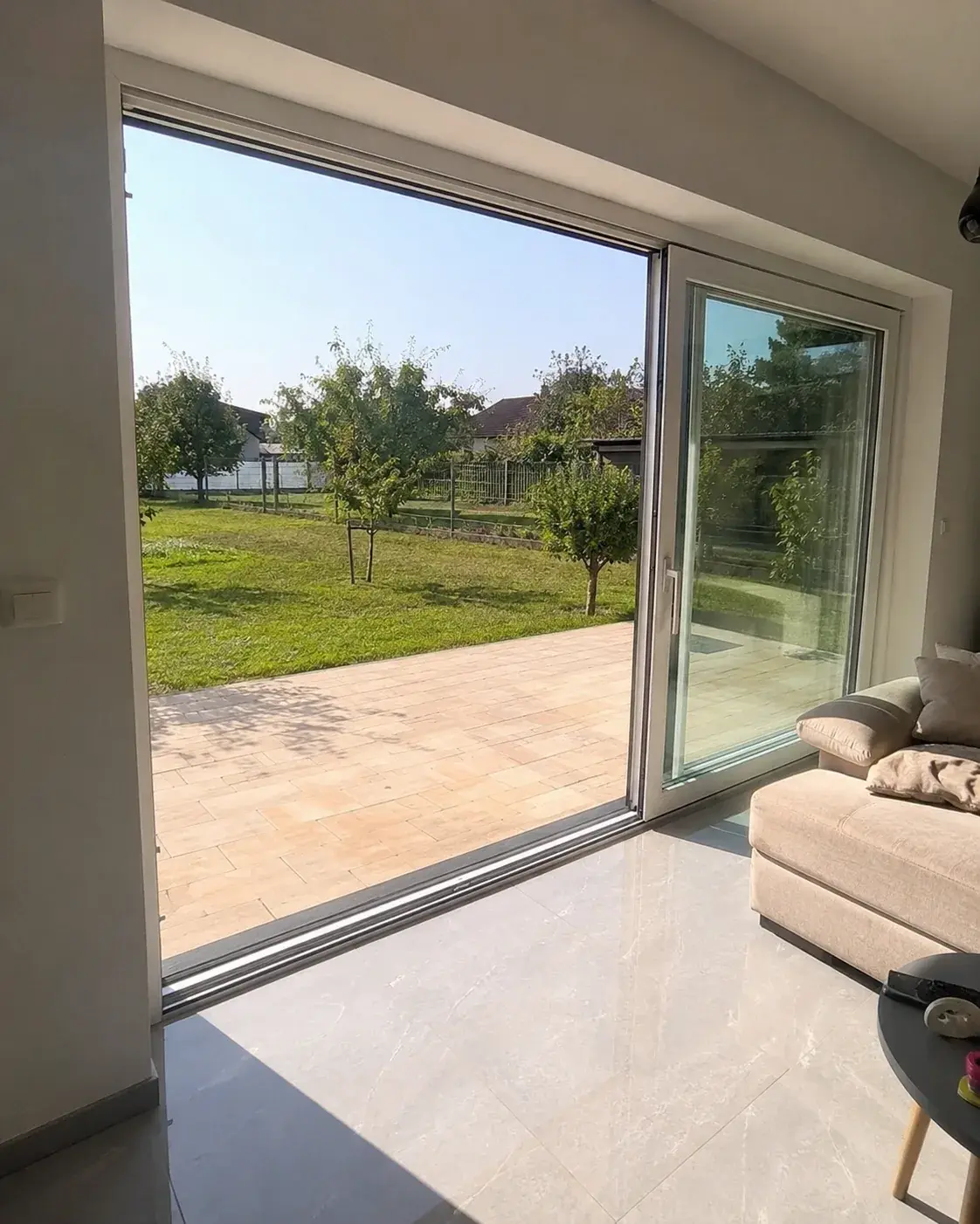 Velika klizna staklena vrata otvorena ka terasi i dvorištu