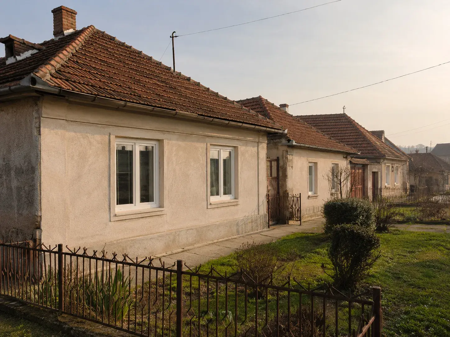 Starija prizemna kuća u ulici sa novim belim PVC prozorima