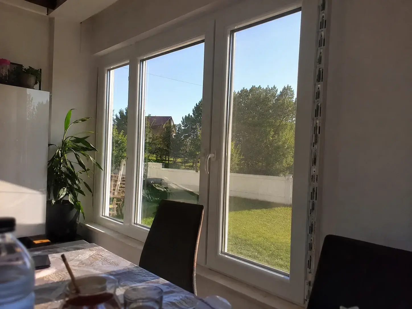 Bela PVC balkonska vrata i prozor u trpezariji sa pogledom na dvorište